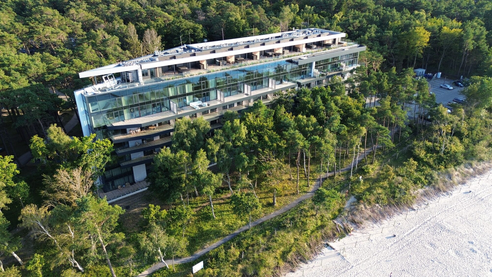 Baltic Jet w Ustroniu Morskim z lotu ptaka, szklany apartamentowiec w sosnowym lesie tuż przy plaży